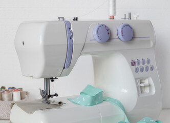 White modern sewing machine on a white table. Tailor's workplace.