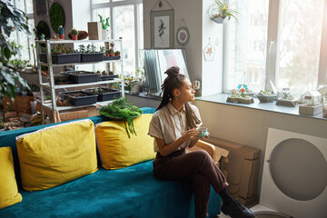 Pensive beautiful florist with cornrows looking out of the window