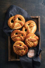 Bavarian pretzels and glass of lager beer. Oktoberfest food menu, traditional salted pretzels over old dark wooden background. Top view with space for text. Oktoberfest theme