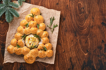 Bread buns Christmas tree with Roasted camembert cheese and rosemary on rustic background. Holiday...