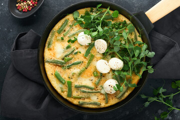 Frittata. Omelet with spinach and green beans, healthy food in black frying pan on dark old rustic background. Healthy breakfast delicious. Top view flat lay. Copy space.