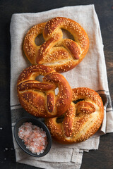 Bavarian pretzels and glass of lager beer. Oktoberfest food menu, traditional salted pretzels over old dark wooden background. Top view with space for text. Oktoberfest theme