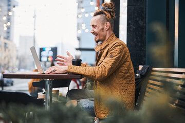 Cheerful young man during video chat outdoors