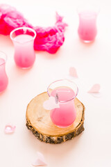 Pink cocktails in glasses and paper hearts on a pink background. Drinks for lovers. Vertical view