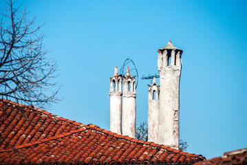 Old roofs and chimneys closeup on blue sky background