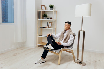 handsome man with a tablet sits in a chair communication Lifestyle