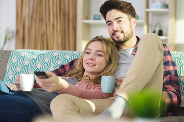 loving couple snuggling on sofa with cup of tea