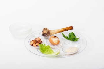 Seder Plate transparent low-angle close-up view with six elements and salt water, on white background