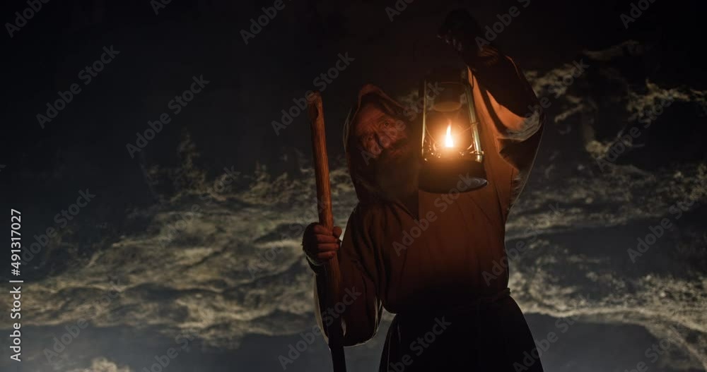 Wall mural silhouette of a mystical monk or a poor man standing with a lantern and drought on the background of