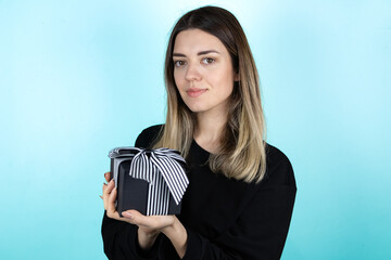Young beautiful girl holding gift box on white isolated background. Black gift box with ribbon. 