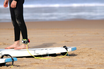 Young people surfing on the beach in summer, board leash