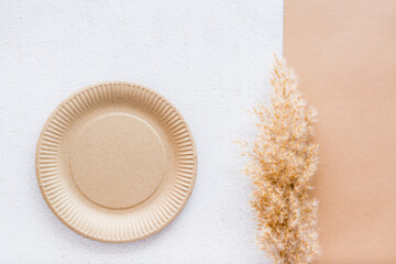 The concept of eco-friendly utensils for food. Cardboard plate and dry grass on plaster and cardboard background. Top view.