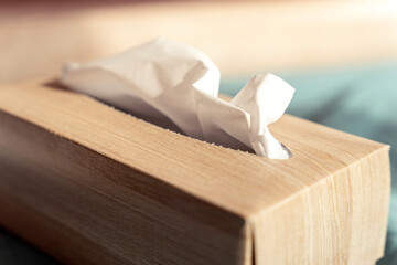 Beige paper tissue box detail with light wooden texture