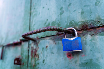 Turquoise blue aged weathered metal surface door with a blue padlock, locked door, background texture
