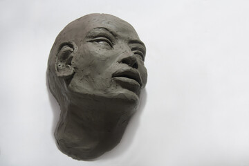 Clay sculpture of head and face on white background. Contemporary art