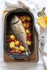 Grilled fish with potatoes and vegetables in a casserole dish