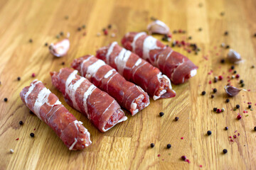 Chevapchichi on the wooden table, top view. Minced meat wrapped in bacon. Kofta kebab