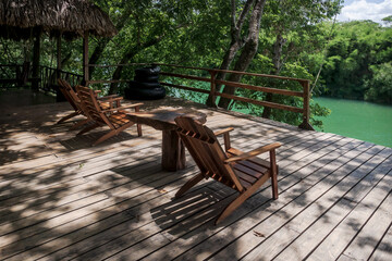 River side jetty with wooden chairs surrounded by lush tropical jungle at Mopan river, Bullet Tree Falls, Belize