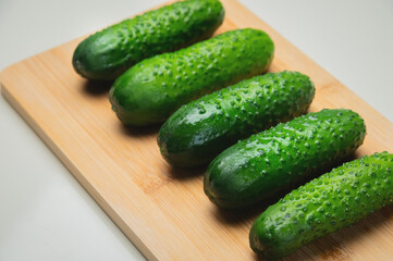 Several fresh green cucumbers on a wooden cutting board
