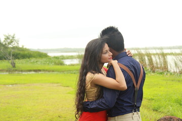 A loving young couple on a beautiful green background. Their clothes are made of blue and red