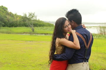 A loving young couple on a beautiful green background. Their clothes are made of blue and red