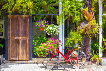 Fototapeta na wymiar Streets of Thailand. Wooden old door and a green wall of flowering plants, old bicycle decor