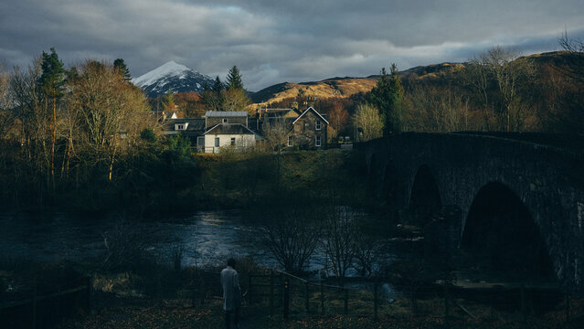 woman and old bridge over the river in the mountains