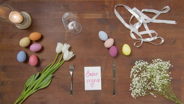 Top view of a table with items to create a composition for Easter. A woman's hand raises a plate with an egg. Easter menu. Church holiday-Easter