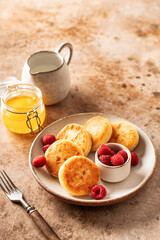 Cottage cheese pancakes syrniki with fresh raspberry on textured background