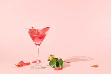 Martini glass and camellia flower on pink pastel background. Minimal party concept. Wedding day or...
