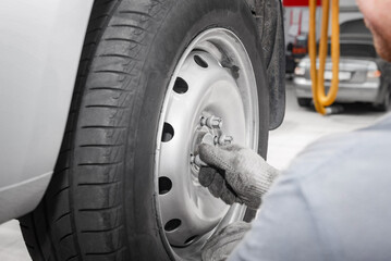 Mechanician changing car wheel in auto repair shop.