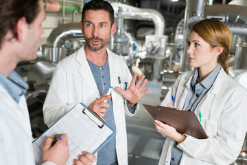 three technicians in discussion holding clipboards