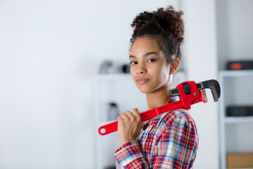 confident young woman carrying adjustable wrench over her shoulder