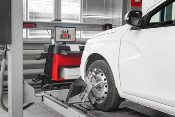 Tire clamped with aligner undergoing auto wheel alignment in garage. - obrazy, fototapety, plakaty