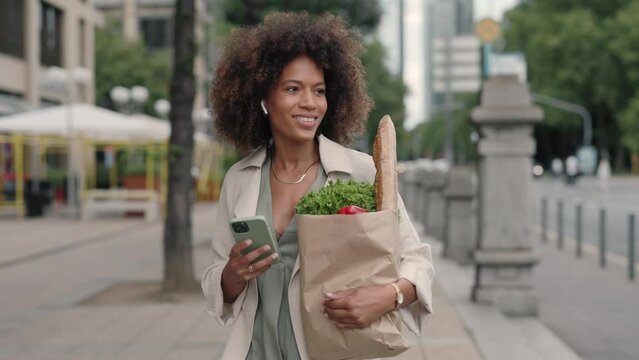 Woman listening music while carrying grocery bag outdoors