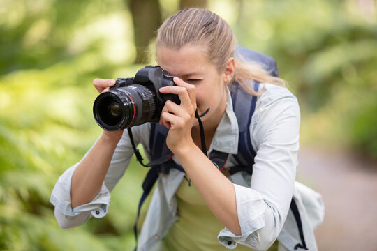female photographer focusing camera in the countryside
