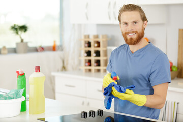 male janitor cleaning kitchen counter with detergent spray