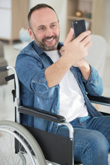handsome man in wheelchair taking a selfie and smiles