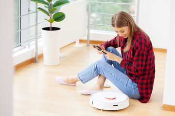 Woman resting while robotic vacuum cleaner doing her work at home - obrazy, fototapety, plakaty