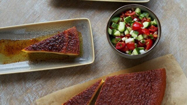 Chickpea flour dish with olive oil and spices with fresh vegetable salad. Moroccan cuisine kalinte meal, table spin.