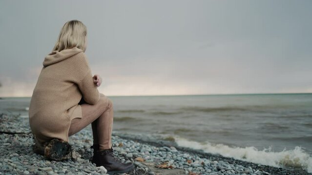 The view from the back of a woman, admiring the stormy sky above the sea. Sits on the shore