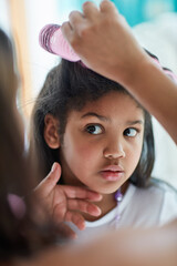 Are you sure about this, mom. Shot of a nervous little girl watching as her mother puts curlers in her hair.