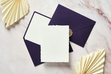 Blank paper card mockup, purple envelopes, dried flowers on stone table. Wedding invitation card...