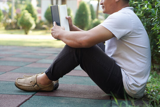 Man is reading book in the park.  Cozy atmosphere. Concept : Relax time, pastime, hobby. Give time for yourself to read books , magazine, novels. Reading in daily life. Education ,knowledge, pleasure