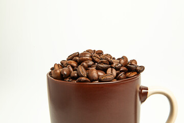 Coffee beans lie in brown mugs. On a white background. Roasted coffee seeds.