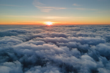 Aerial view from above at high altitude of dense puffy cumulus clouds flying in evening. Amazing...