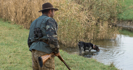 Hunter man in camouflage with a gun during the hunt in search of wild birds or game. Autumn hunting...