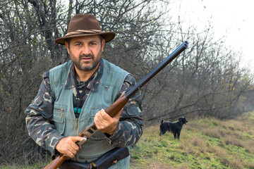 Hunter man in camouflage with a gun during the hunt in search of wild birds or game. Autumn hunting...