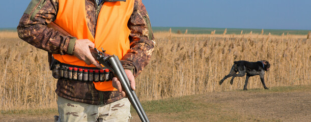 Hunter man in camouflage with a gun during the hunt in search of wild birds or game. Autumn hunting...
