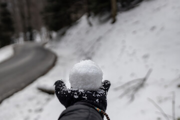 Mão com luvas no inverno segurando bola de neve.